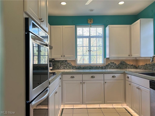 kitchen featuring a sink, tasteful backsplash, white cabinets, and stainless steel appliances