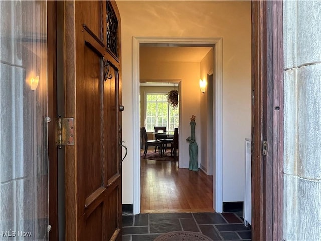 hall featuring baseboards and stone finish floor