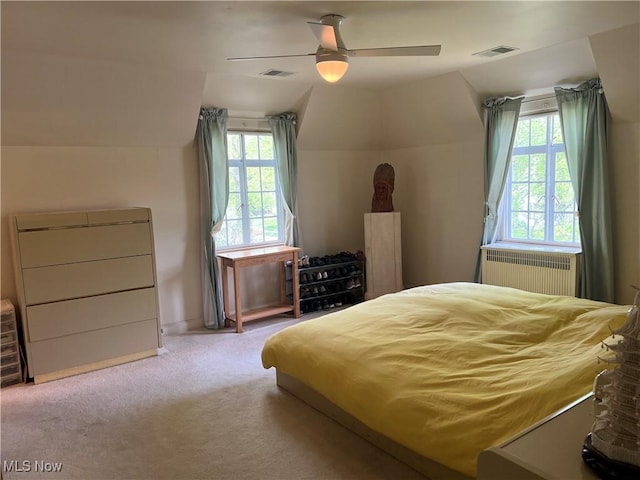 carpeted bedroom with radiator heating unit, multiple windows, and visible vents