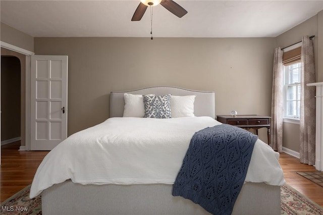 bedroom with baseboards, arched walkways, ceiling fan, and wood finished floors