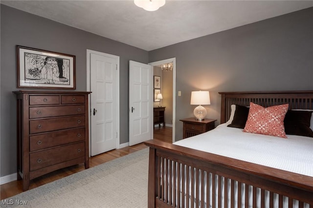 bedroom with baseboards, a notable chandelier, and wood finished floors
