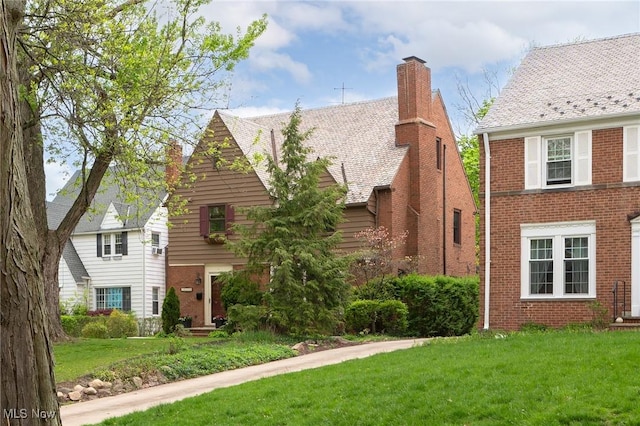 view of front facade with brick siding, a front yard, and a chimney