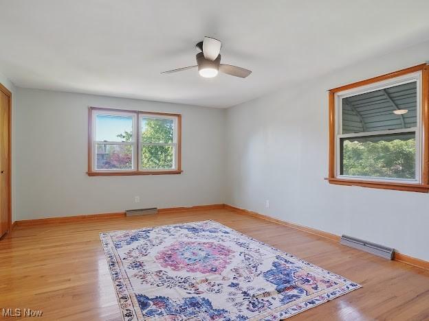 spare room featuring baseboards, ceiling fan, light wood finished floors, and visible vents
