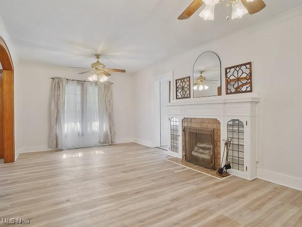 unfurnished living room with baseboards, ceiling fan, wood finished floors, and a fireplace