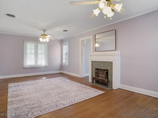 unfurnished living room featuring a ceiling fan, baseboards, ornamental molding, and wood finished floors