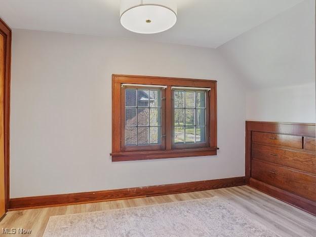 bonus room featuring baseboards, lofted ceiling, and light wood finished floors