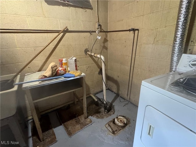 clothes washing area featuring washer / dryer and concrete block wall