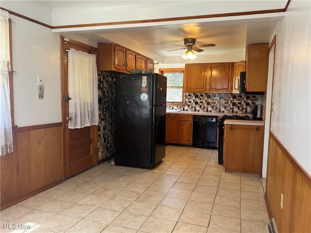 25911 Tryon Rd, Oakwood Village, OH 44146 - kitchen featuring black appliances, brown cabinetry, a wainscoted wall, ceiling fan, and light countertops