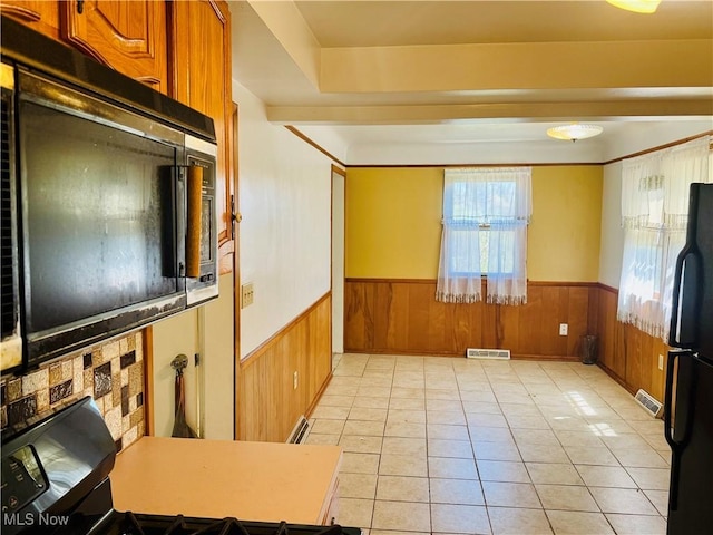 25911 Tryon Rd, Oakwood Village, OH 44146 - kitchen with a wainscoted wall, freestanding refrigerator, brown cabinets, light tile patterned floors, and wood walls