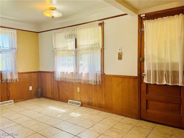 unfurnished room featuring visible vents, light tile patterned floors, and a wainscoted wall