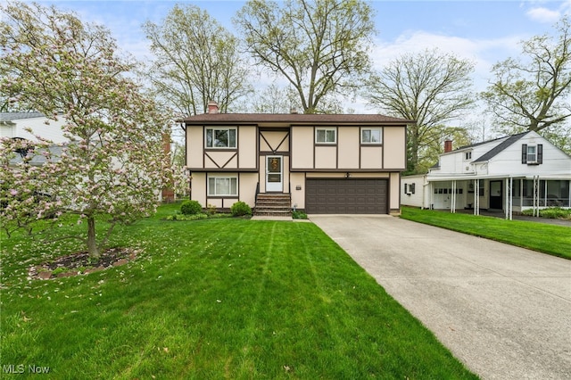 split foyer home featuring a garage, a front lawn, stucco siding, a chimney, and concrete driveway