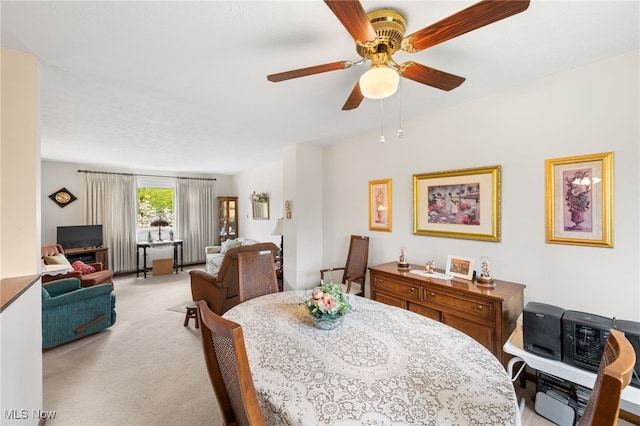 dining space featuring light carpet and a ceiling fan