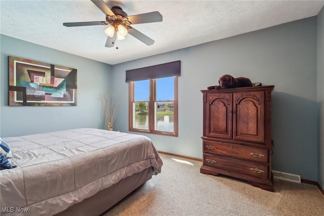 bedroom featuring baseboards, visible vents, a textured ceiling, and light colored carpet