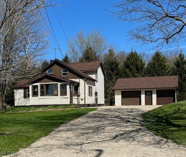 view of front of home featuring an outdoor structure, a garage, a front lawn, and aphalt driveway