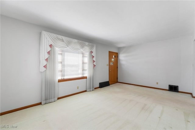 carpeted spare room featuring visible vents and baseboards