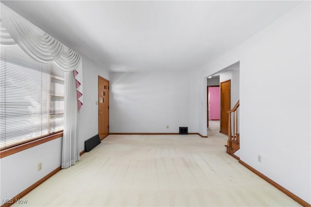 empty room with light colored carpet, baseboards, and visible vents