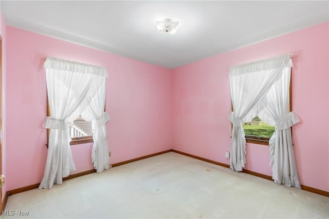 unfurnished room featuring baseboards, plenty of natural light, and carpet