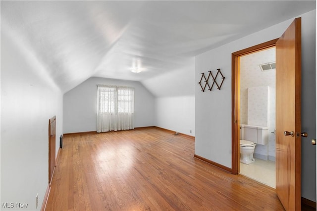 additional living space with light wood-style floors, baseboards, and vaulted ceiling