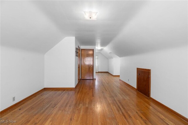 additional living space with baseboards, vaulted ceiling, and wood finished floors