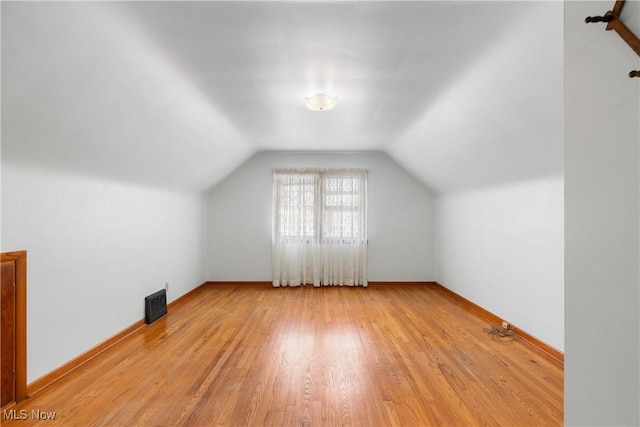 additional living space with baseboards, lofted ceiling, and light wood-style floors