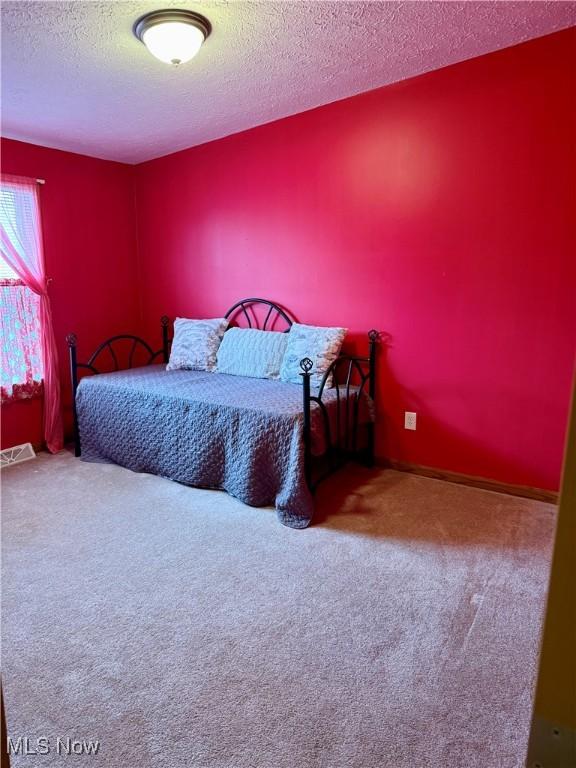 bedroom featuring carpet flooring and a textured ceiling