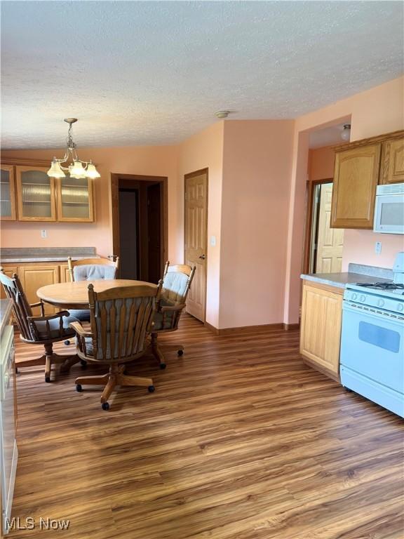 dining room with baseboards, a textured ceiling, a notable chandelier, and wood finished floors