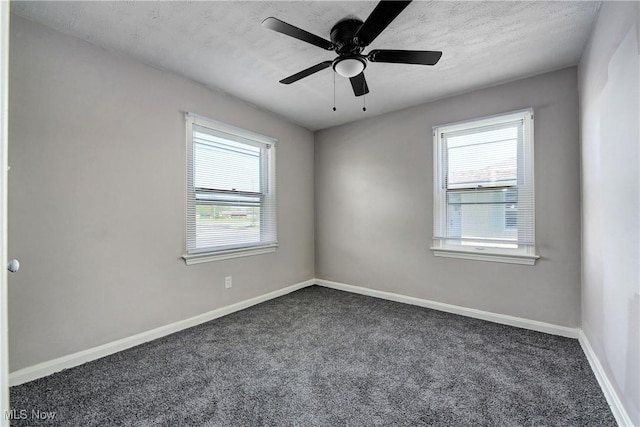 unfurnished room featuring a healthy amount of sunlight, baseboards, and dark carpet