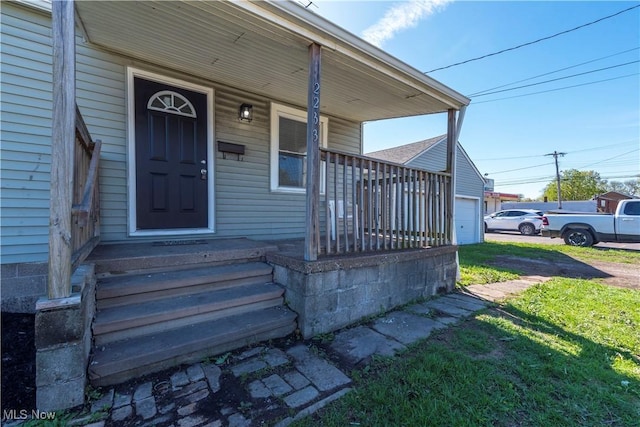 entrance to property featuring a porch, a yard, and an attached garage
