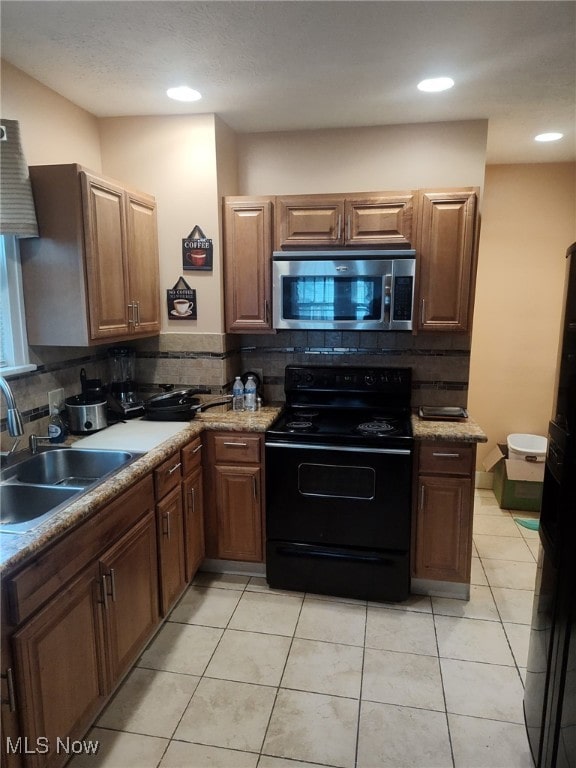 916 Mercer Ave, Akron, OH 44320 - kitchen featuring stainless steel microwave, electric range, a sink, decorative backsplash, and light tile patterned floors