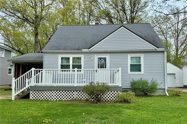 rear view of property with a lawn, a deck, a shingled roof, and a chimney