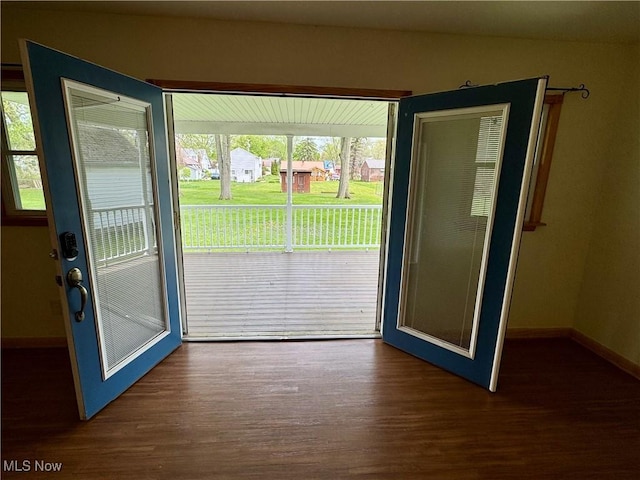 doorway with baseboards and wood finished floors