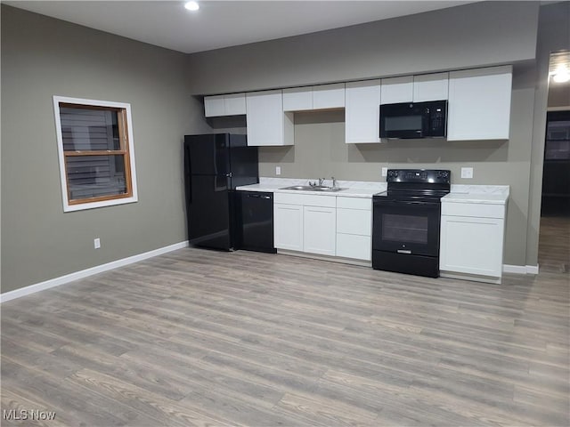 kitchen with light wood-style floors, baseboards, black appliances, and white cabinetry