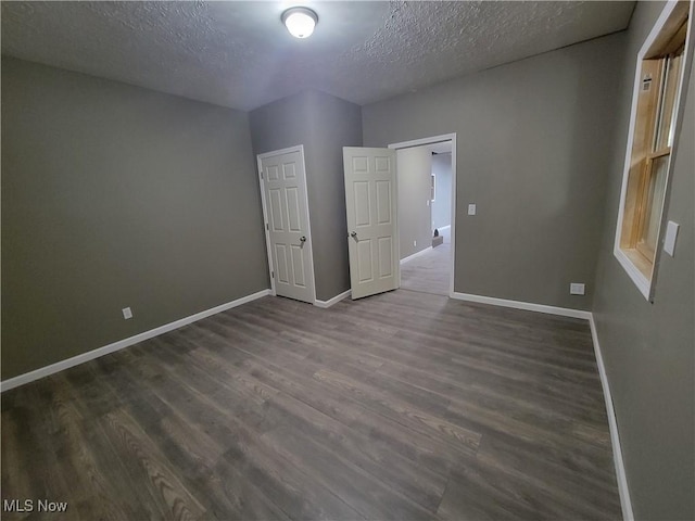 unfurnished bedroom with baseboards, dark wood finished floors, and a textured ceiling