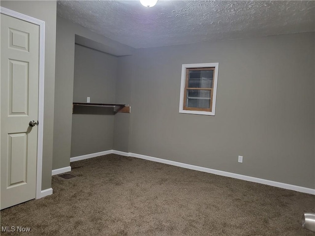empty room featuring carpet floors, a textured ceiling, visible vents, and baseboards