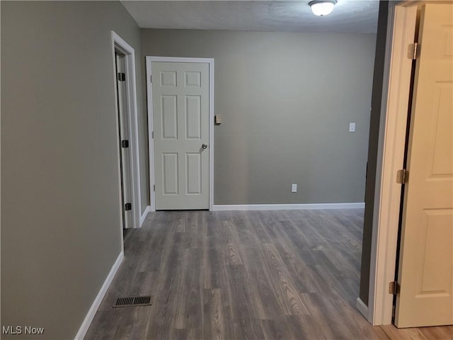hall featuring baseboards, visible vents, and wood finished floors
