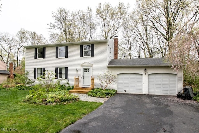 colonial inspired home featuring an attached garage, a front lawn, aphalt driveway, and a chimney