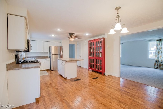 kitchen with appliances with stainless steel finishes, recessed lighting, white cabinetry, a kitchen island, and pendant lighting