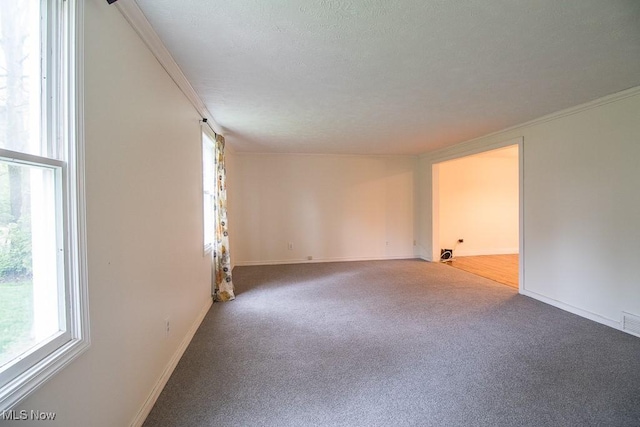 carpeted spare room featuring baseboards, ornamental molding, and visible vents