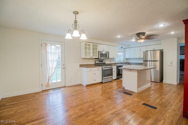 kitchen featuring visible vents, baseboards, light wood-type flooring, a sink, and stainless steel appliances