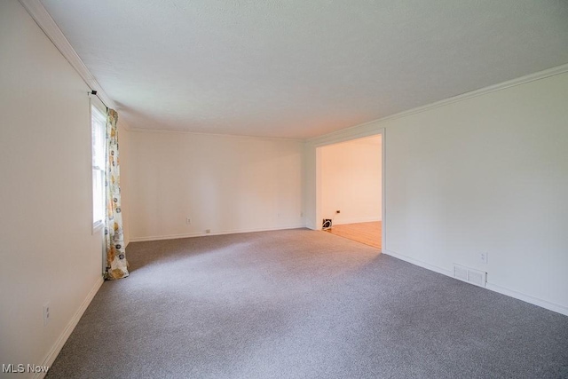 unfurnished room with carpet floors, crown molding, visible vents, and baseboards