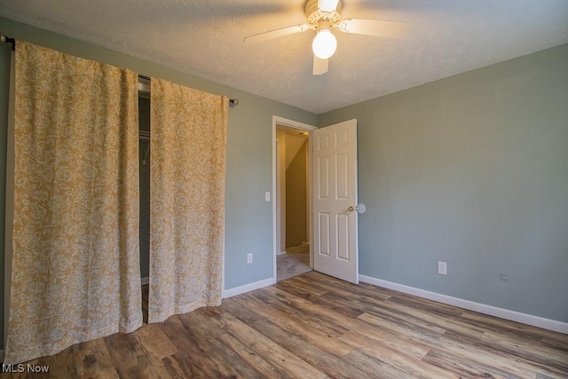 unfurnished bedroom with baseboards, a ceiling fan, a textured ceiling, and wood finished floors