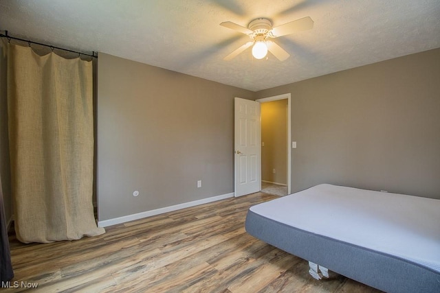 bedroom with baseboards, a textured ceiling, ceiling fan, and wood finished floors