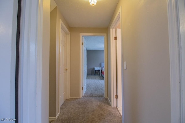 hall with baseboards and light carpet