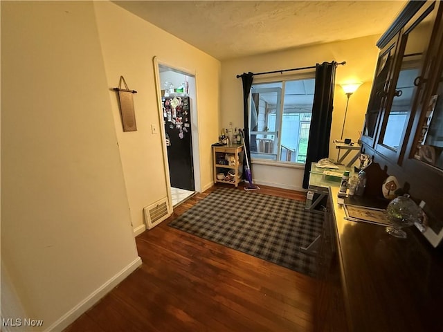 corridor featuring baseboards, dark wood finished floors, and visible vents