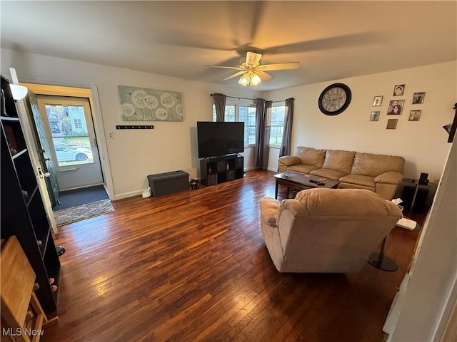 living area featuring baseboards, wood-type flooring, and a ceiling fan