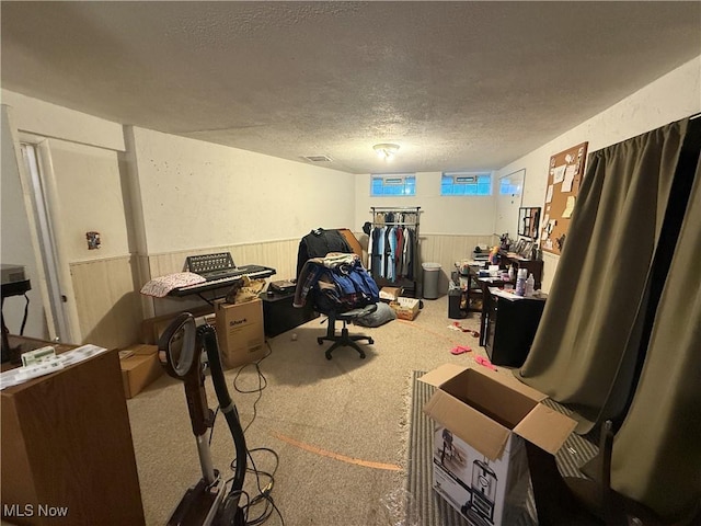 carpeted home office with a textured ceiling and a wainscoted wall
