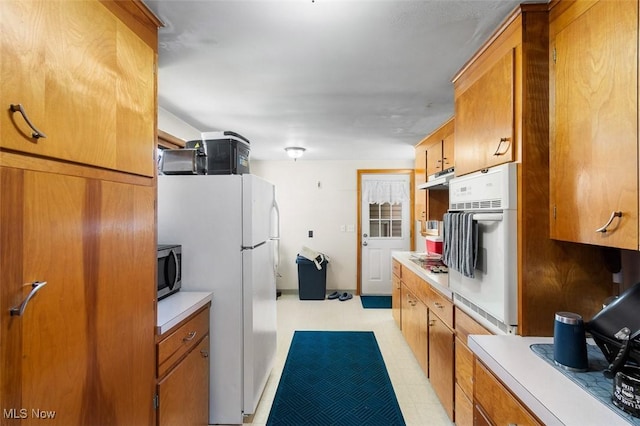 kitchen featuring light countertops, appliances with stainless steel finishes, under cabinet range hood, and brown cabinets