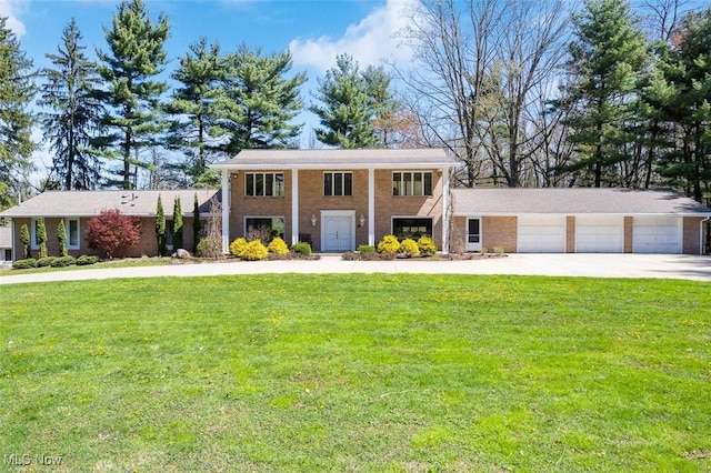 neoclassical / greek revival house featuring brick siding, a garage, a front lawn, and driveway