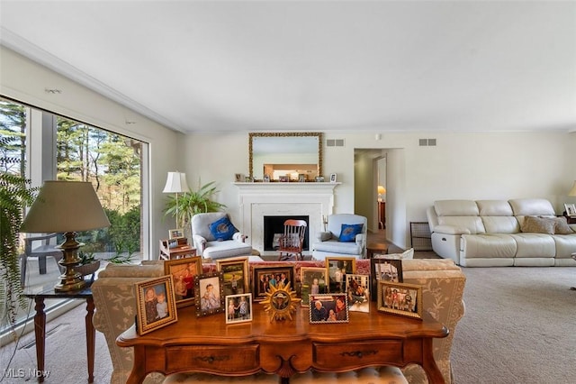 living room featuring a fireplace, ornamental molding, carpet, and visible vents
