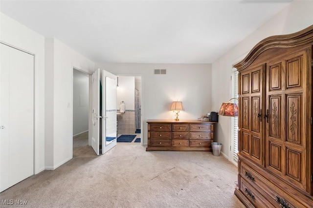 bedroom with light colored carpet, connected bathroom, baseboards, and visible vents